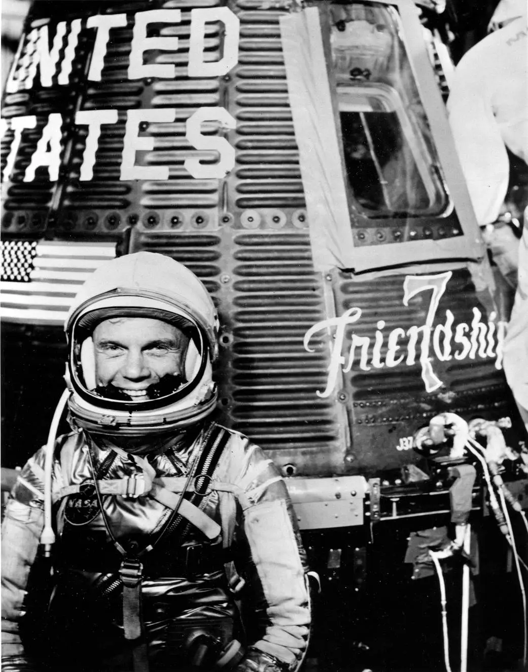 John Glenn in his Mercury pressure suit beside the Friendship 7 capsule